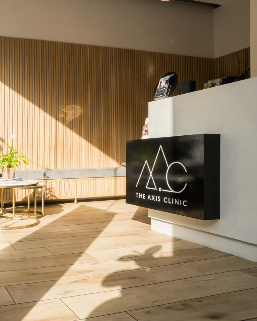 Modern lounge area at The Axis Clinic featuring elegant seating, indoor plants, and warm wooden wall design.
